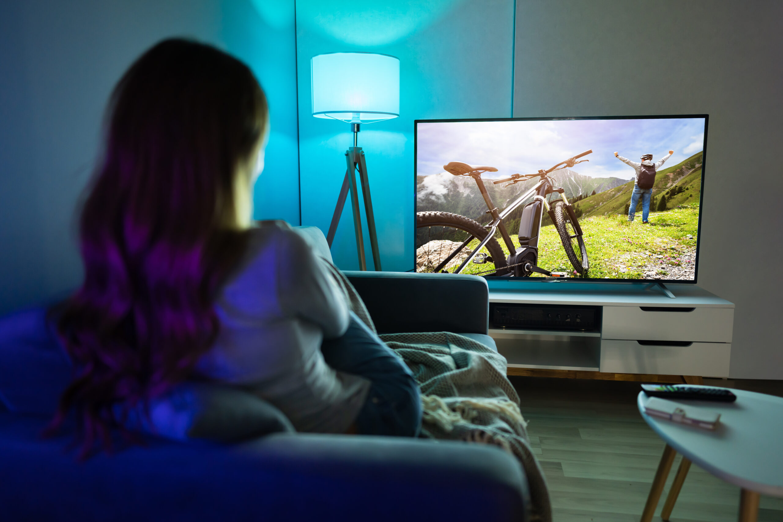 Young Woman Sitting On Carpet Watching Movie On Television At Home